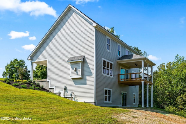 rear view of property with a yard, ceiling fan, and a balcony