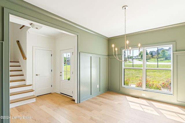 interior space featuring ornamental molding, light hardwood / wood-style flooring, and a notable chandelier