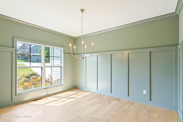 unfurnished dining area with crown molding, light wood-type flooring, and a chandelier