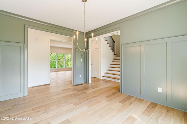 unfurnished dining area featuring light wood-type flooring and a notable chandelier