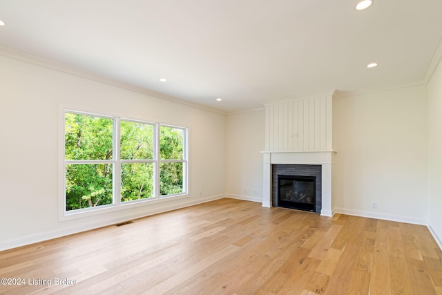 unfurnished living room featuring light wood-type flooring, a fireplace, and ornamental molding