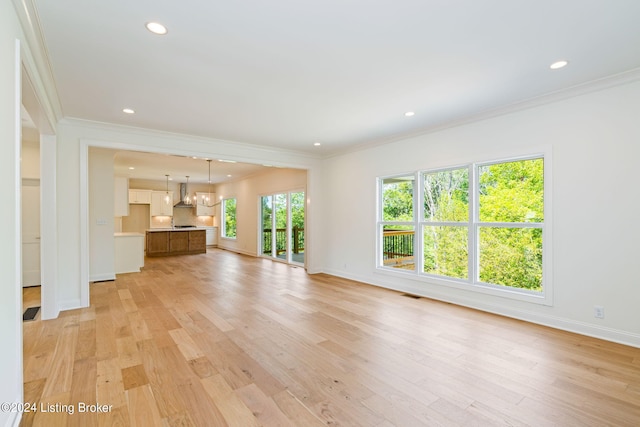 unfurnished living room featuring a wealth of natural light, light hardwood / wood-style floors, and ornamental molding