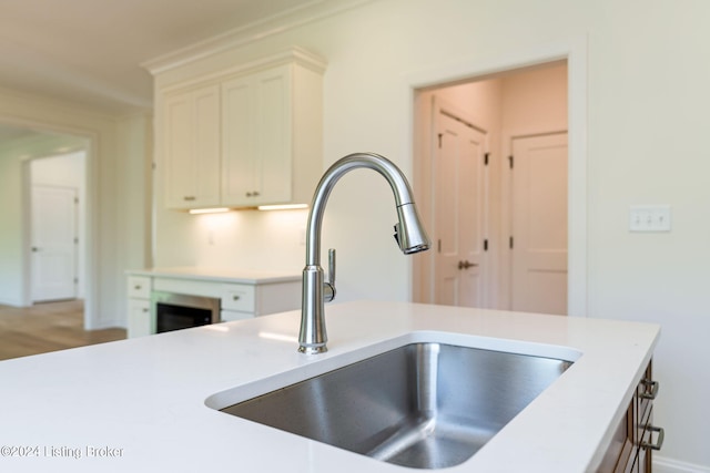 kitchen with white cabinets, wood-type flooring, and sink