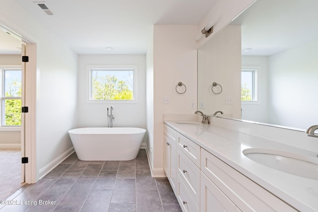 bathroom featuring tile patterned flooring, plenty of natural light, a bathtub, and vanity