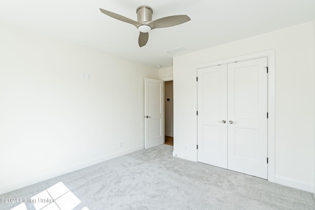 unfurnished bedroom with ceiling fan, a closet, and light carpet