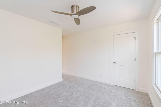 spare room featuring light carpet, plenty of natural light, and ceiling fan