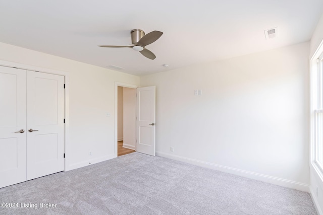 unfurnished bedroom with ceiling fan, a closet, and light carpet