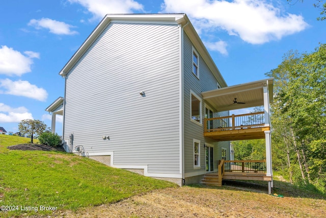 view of side of home featuring ceiling fan, a yard, and a wooden deck