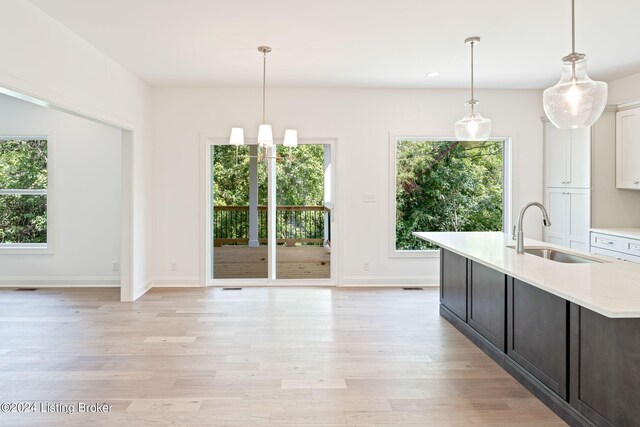 kitchen featuring white cabinets, hanging light fixtures, light hardwood / wood-style floors, and sink