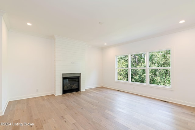 unfurnished living room with a large fireplace, light hardwood / wood-style floors, and ornamental molding