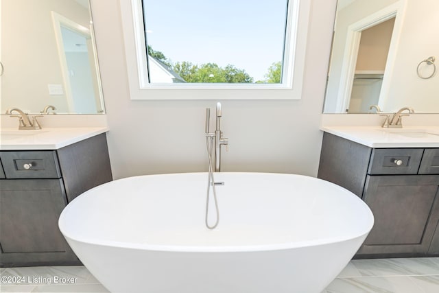 bathroom with a tub to relax in, vanity, and a healthy amount of sunlight