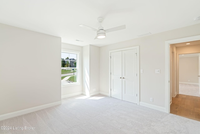 unfurnished bedroom featuring light carpet, ceiling fan, and a closet