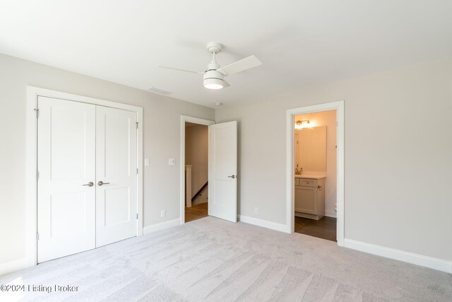 unfurnished bedroom featuring a closet, ceiling fan, connected bathroom, and light carpet