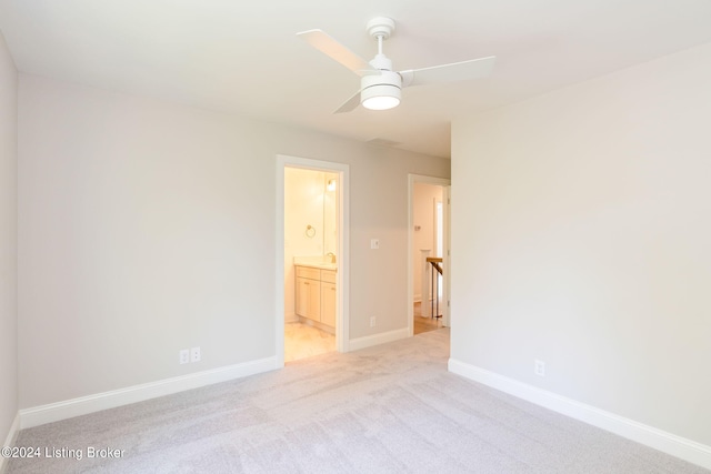 unfurnished bedroom featuring light colored carpet, ceiling fan, and ensuite bathroom