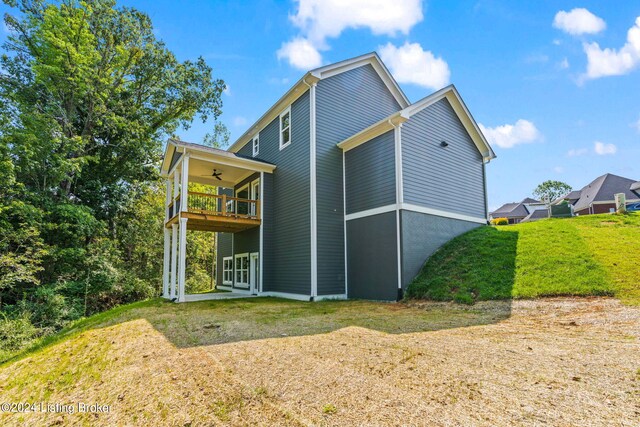 rear view of property with a balcony, a lawn, and ceiling fan