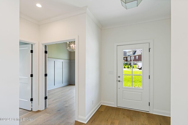 entryway featuring an inviting chandelier, light hardwood / wood-style floors, and crown molding