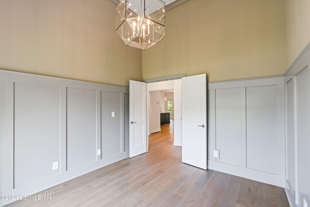 6715 Hypoint Ridge Rd, Crestwood, KY 40014 - unfurnished bedroom with a decorative wall, a towering ceiling, a notable chandelier, and wood finished floors