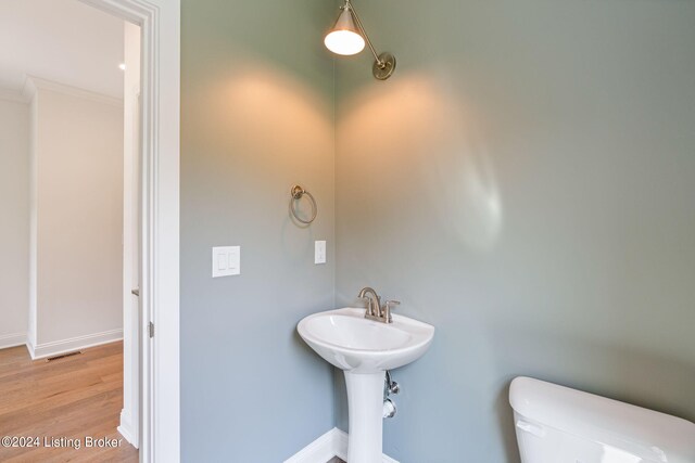 bathroom featuring hardwood / wood-style floors, toilet, and ornamental molding