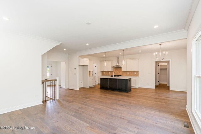 unfurnished living room featuring crown molding, sink, light wood-type flooring, and an inviting chandelier