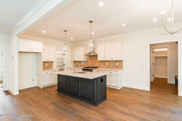 kitchen featuring hardwood / wood-style flooring, white cabinetry, sink, a kitchen island with sink, and ornamental molding