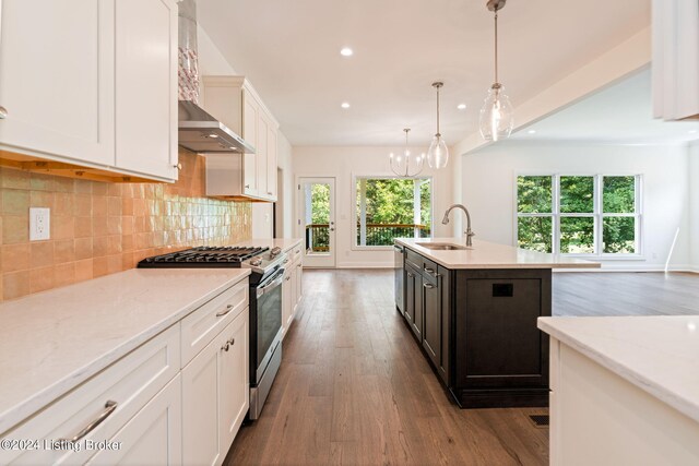 kitchen featuring appliances with stainless steel finishes, light hardwood / wood-style floors, an island with sink, sink, and wall chimney range hood