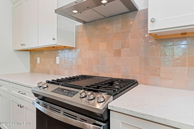 kitchen with white cabinetry, tasteful backsplash, range hood, light stone countertops, and gas range