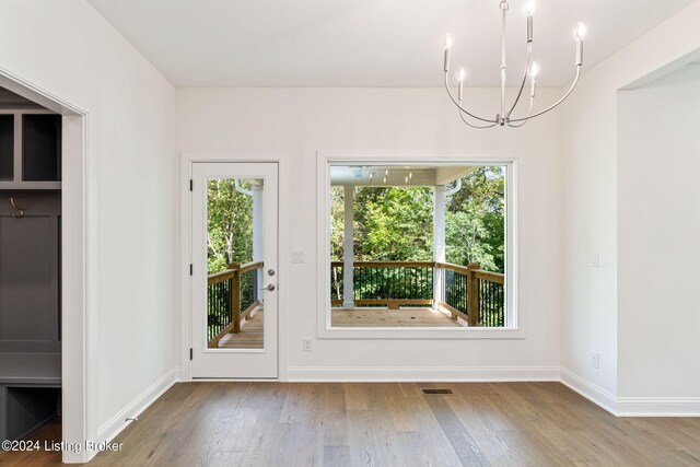 doorway to outside featuring a healthy amount of sunlight, light hardwood / wood-style flooring, and an inviting chandelier