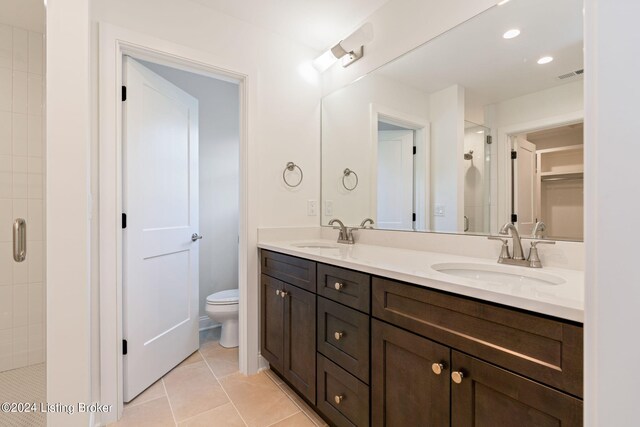 bathroom with vanity, toilet, a shower with shower door, and tile patterned flooring