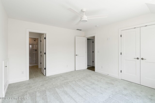 unfurnished bedroom with light carpet, ensuite bathroom, ceiling fan, and a closet