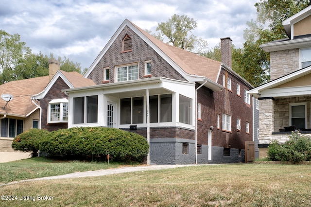 view of front of property featuring a sunroom and a front lawn