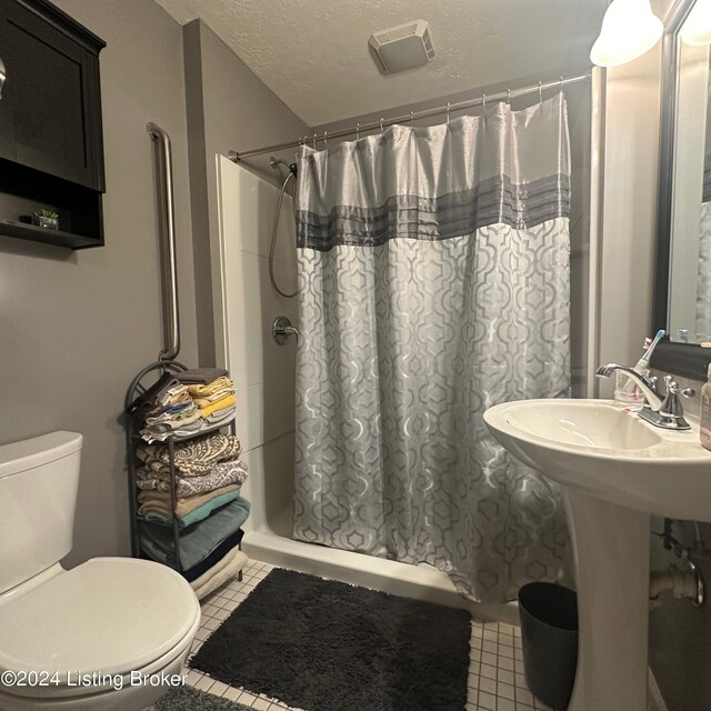 bathroom with tile patterned flooring, toilet, a shower with curtain, and a textured ceiling