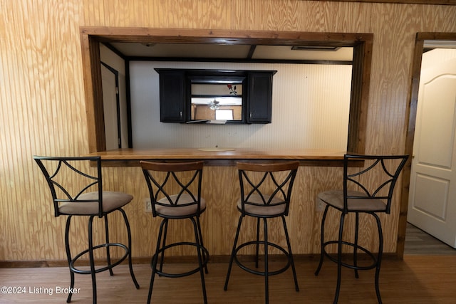 bar with hardwood / wood-style flooring and wooden walls