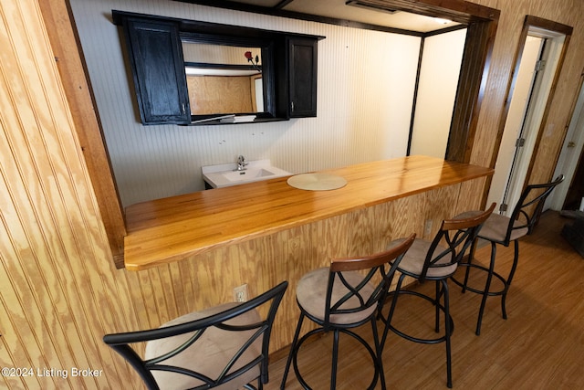 bar with sink, wood-type flooring, and wooden walls