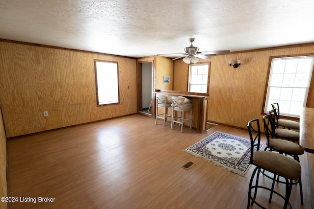 living room with a textured ceiling, ceiling fan, wood walls, and hardwood / wood-style floors