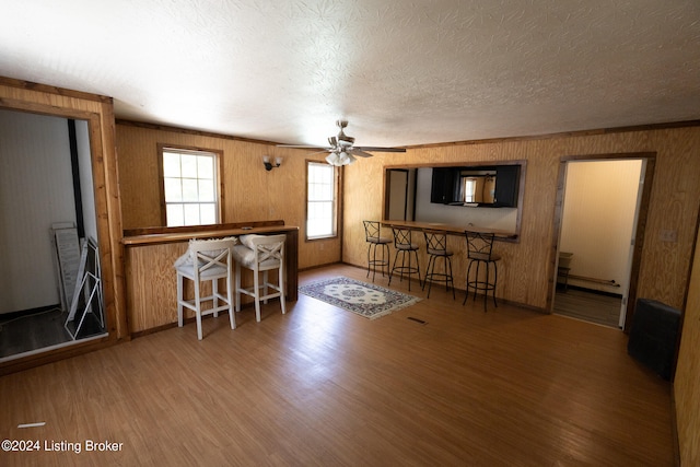 unfurnished living room with ceiling fan, hardwood / wood-style flooring, ornamental molding, and a textured ceiling