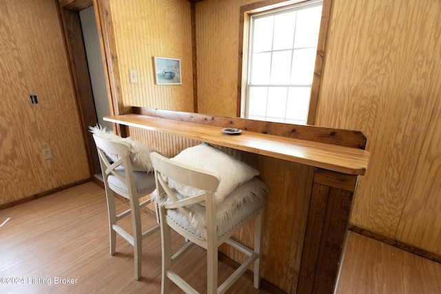 bar with wood walls, light hardwood / wood-style floors, and wood counters