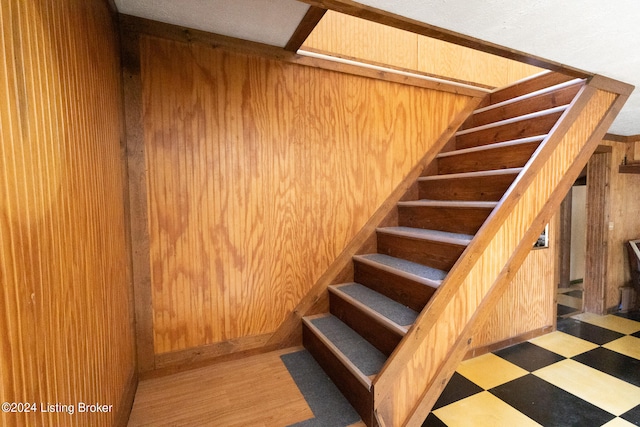 stairway featuring hardwood / wood-style floors and wooden walls