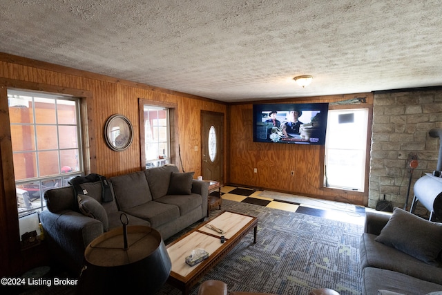 living room with a textured ceiling, wood walls, and a wood stove