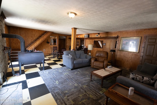 living room featuring a wood stove, wooden walls, and a textured ceiling