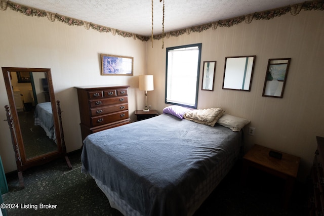 bedroom with dark carpet and a textured ceiling