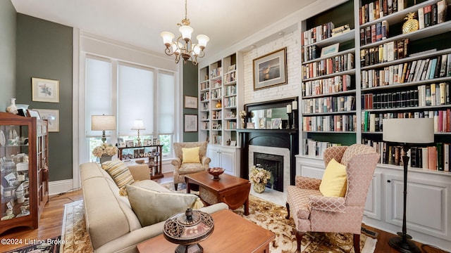 living area with ornamental molding, a notable chandelier, built in features, and light hardwood / wood-style floors