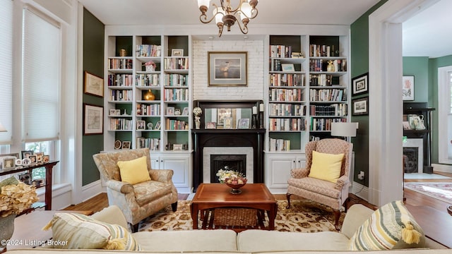 sitting room with built in shelves, an inviting chandelier, and hardwood / wood-style flooring