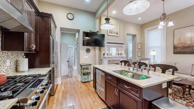 kitchen featuring a kitchen bar, light hardwood / wood-style flooring, hanging light fixtures, and stainless steel appliances