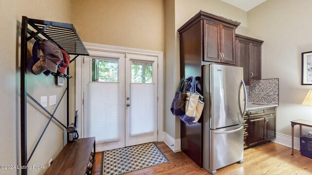 kitchen featuring stainless steel fridge, decorative backsplash, dark brown cabinets, and light hardwood / wood-style flooring