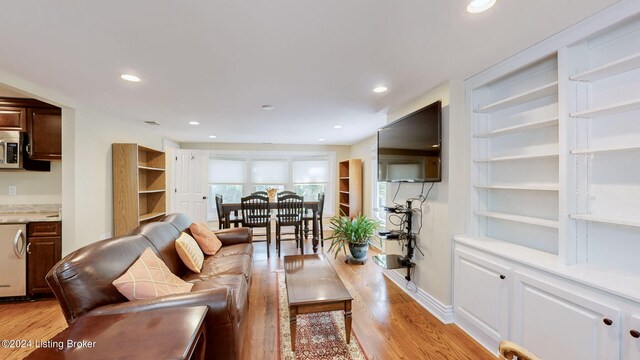 living room featuring light wood-type flooring and built in shelves