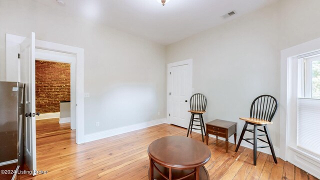 living area featuring light wood-type flooring and brick wall