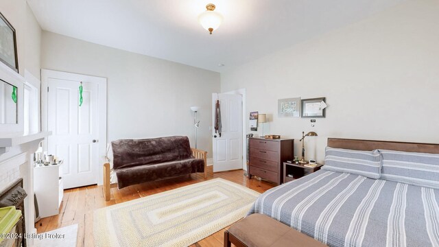 bedroom with light hardwood / wood-style flooring and a fireplace