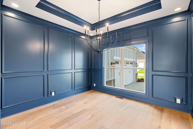 spare room with crown molding, light hardwood / wood-style floors, and a raised ceiling