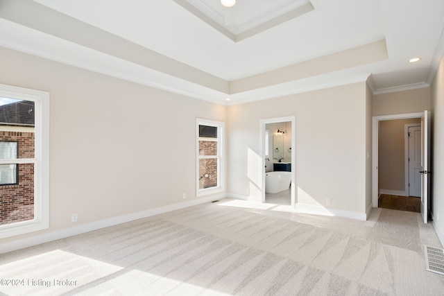 unfurnished bedroom with light carpet, crown molding, ensuite bath, and a tray ceiling