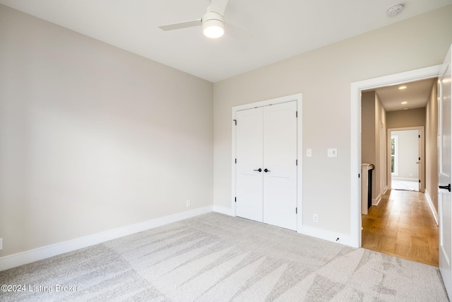 unfurnished bedroom featuring a closet, light wood-type flooring, and ceiling fan